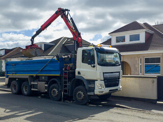A grab lorry, a grab hire truck is a specialized vehicle with a hydraulic arm, bucket for efficiently loading and transporting large amounts of waste materials. Residential area, for waste removal. 