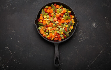 Frozen mixed vegetables including chopped carrots, green beans, corn, bell pepper in a cast iron skillet, ready for healthy cooking
