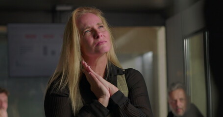 Blonde businesswoman struggling with emotional distress in office, holding head and clenching fists...