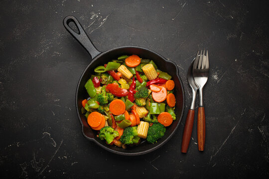 Colorful vegetables broccoli carrot green beans bell pepper stir fried in a cast iron skillet, presenting a healthy and fresh vegetarian meal
