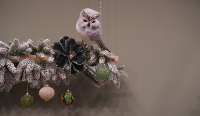 Vintage Owl Figurine and Balls on a Spruce Branch on a Gray Background with Free Space for Inserting Winter Holiday Greetings Text