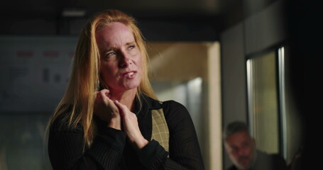 Blonde businesswoman showing emotional vulnerability in office, eyes closed and hands clenched in...