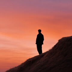 Fototapeta premium Silhouette of male figure against vibrant sunset sky on hilltop