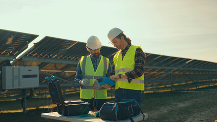 Engineers inspect solar panels at a renewable energy site during afternoon hours in a sunny location