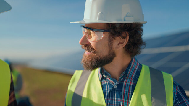 Team members discuss project at solar energy site during sunny afternoon in rural landscape