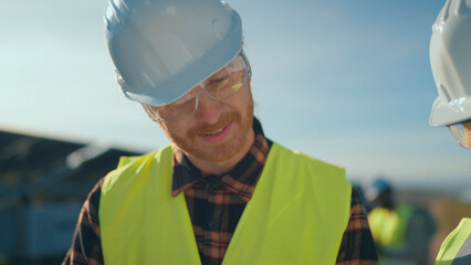 Construction workers inspect plans on a bright day at a building site in the countryside