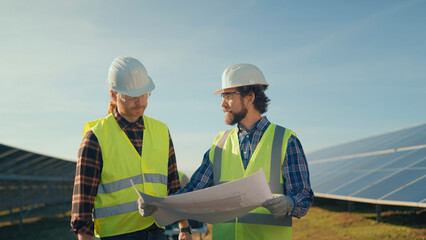 Engineers discussing solar panel layout at a construction site in the afternoon sun