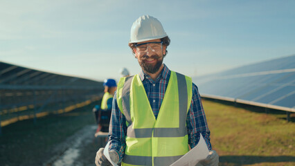 Solar energy technician reviewing plans at a solar farm in bright sunlight © Videophilia