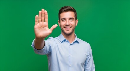 Man showing stop hand gesture with five fingers, smiling happily to camera. Green screen studio background for chroma key editing.