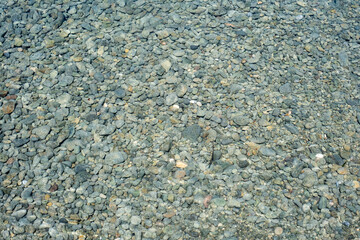 Crystal clear water over riverbed stones creating serene natural texture