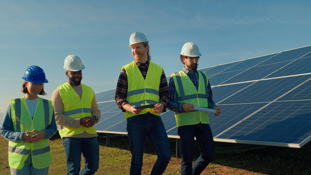 Professionals discuss solar energy project during daytime at solar panel installation site, emphasizing teamwork and renewable energy solutions