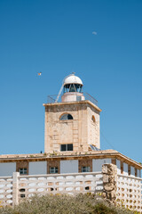 Historic lighthouse under clear blue sky with drone and moon in background