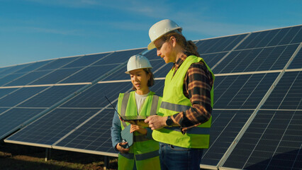 Professionals analyze solar panel data at a renewable energy site during a sunny afternoon