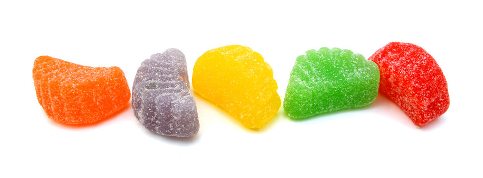 Colorful fruit jelly candies lined up on a white background offer a sugary sweet treat, inviting indulgence and joyful moments of deliciousness