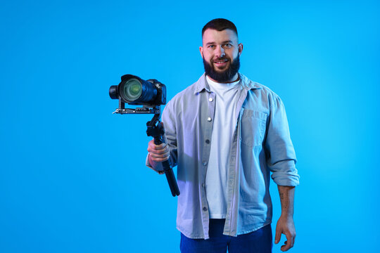 Videographer using gimbal stabilizer with camera on light blue background