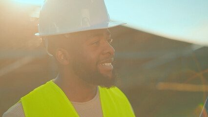 Construction worker smiles during teamwork on a sunny day at the building site with safety gear