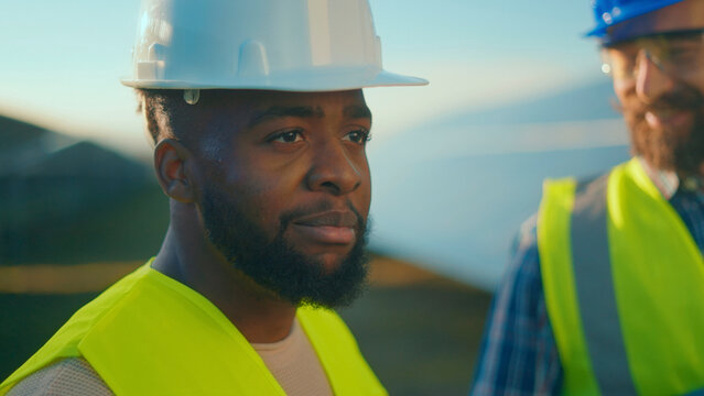 Construction workers collaborating on a project in a sunny outdoor setting with clear sky and safety gear