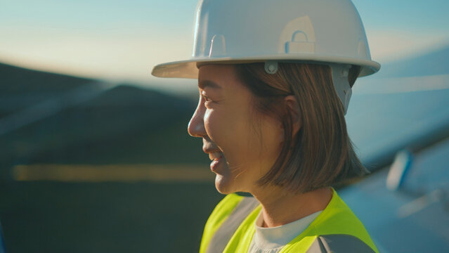 Engineer wears safety gear while working on renewable energy project in sunny outdoor location during late afternoon hours