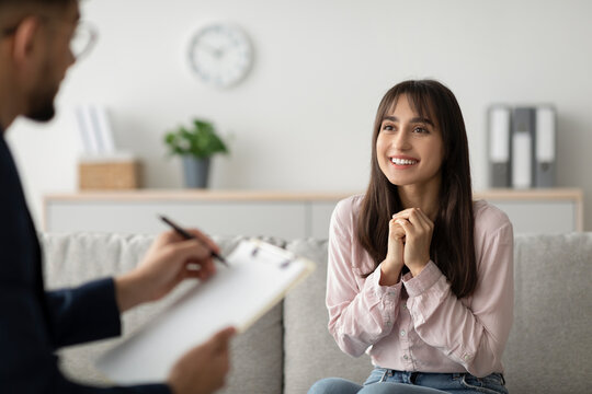 A cheerful arab woman engages with her psychologist during a therapy session. She shares her progress and experiences while receiving professional support in a calming office environment. - Powered by Adobe