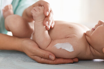Fototapeta premium Mother applying cream onto her baby's arm on changing table at home, closeup