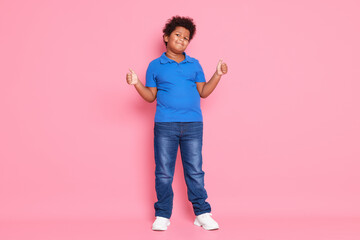 Cute little boy showing thumbs up on pink background