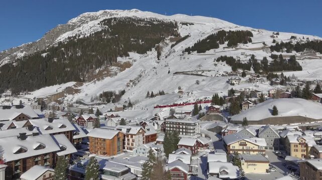 Andermatt, Switzerland in Winter. Aerial of mountain village in Swiss alps in Canton Uri on sunny day after snow fall. 
