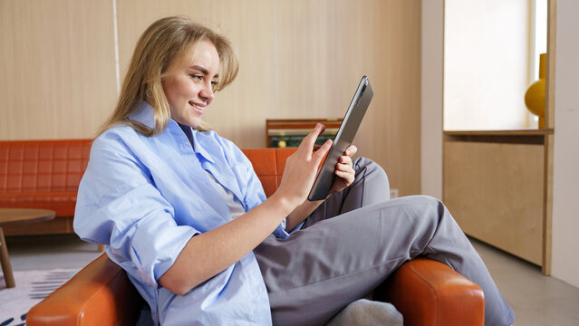 Young woman enjoys tablet while relaxing at home - Powered by Adobe