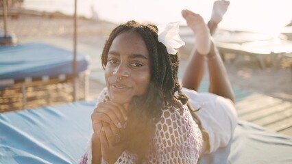 African American woman relaxing on a sunbed at the beach during golden hour, enjoy the warmth of the sun while embracing the tranquil atmosphere