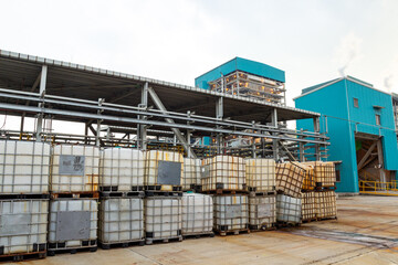 Outdoor storage area of a modern chemical manufacturing plant with stacked Intermediate Bulk Containers