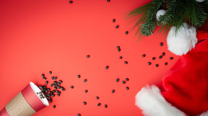 Santa hat and paper cup with coffee beans spilling out.  Mr. Claus wants coffee, not milk, holiday background.