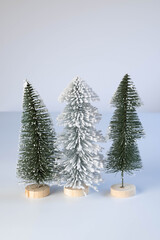 Three miniature trees, one snow covered.  Minimalism.  Simple holiday background or greeting. Vertical.