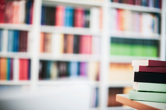 Stack of books in office with book shelf in background