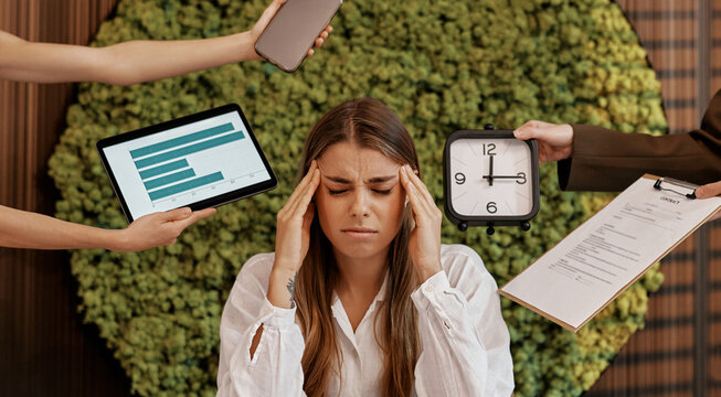 Stressed businesswoman overwhelmed with tasks in modern office