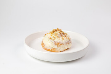Cinnabon roll with cream cheese glaze and crumb topping on white plate against clean background
