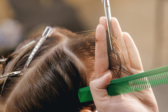 Closeup of young caucasian boy haircut and styling with scissors and comb in barber shop
