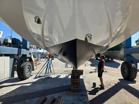 Applying new bottom antifouling paint on boat hull.