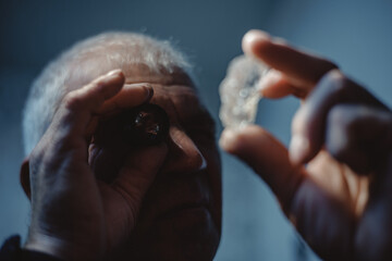 Mature jewelry caucasian male inspecting rough diamond with loupe