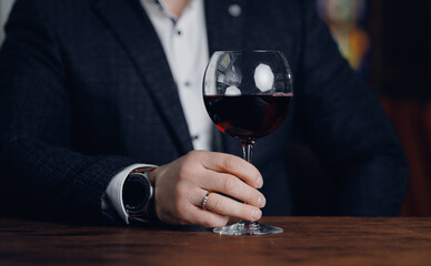 Caucasian male sommelier holding red wine glass at elegant tasting event