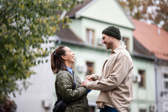 Happy diverse couple laughing and holding hands dating outdoors - Powered by Adobe
