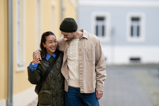 Happy couple walking street together showing affection - Powered by Adobe