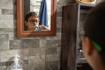 Latin american boy brushing teeth in bathroom mirror, practicing dental hygiene routine