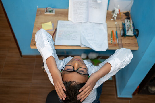 Overwhelmed student boy relaxing while studying at home, feeling stressed by homework