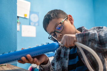 Young mexican boy learning music, concentrating on playing a melodica instrument