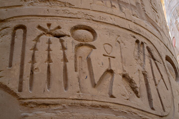 Egypt, Luxor, 01.02.2022.Tall ancient Egyptian temple columns decorated with colorful hieroglyphs and painted figures illuminated by bright sunlight, creating a warm historic atmosphere.