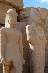 Egypt, Luxor, 01.02.2022.Ancient Egyptian stone statues standing and seated among sandstone temple ruins with carved hieroglyphs and warm light, Karnak temple.