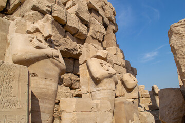 Egypt, Luxor, 01.02.2022.Ancient Egyptian stone statues standing and seated among sandstone temple ruins with carved hieroglyphs and warm light, Karnak temple.