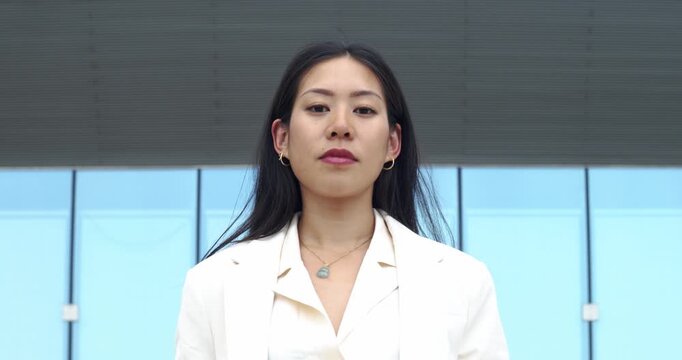 Serious portrait of a young Asian businesswoman looking directly at the camera, showing confidence and professionalism.