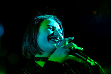 Female singer performing live under green stage lighting