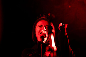 Female rock singer performing on stage with intense red lighting