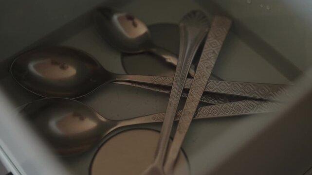 Close-up of kitchen utensils peeler and corkscrew immersed in ultrasonic cleaner, bubbling and vibrating for deep, efficient sanitation and sparkling, professional hygiene. Shooting in slow motion.